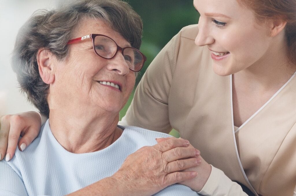 Caregiver comforting smiling senior woman